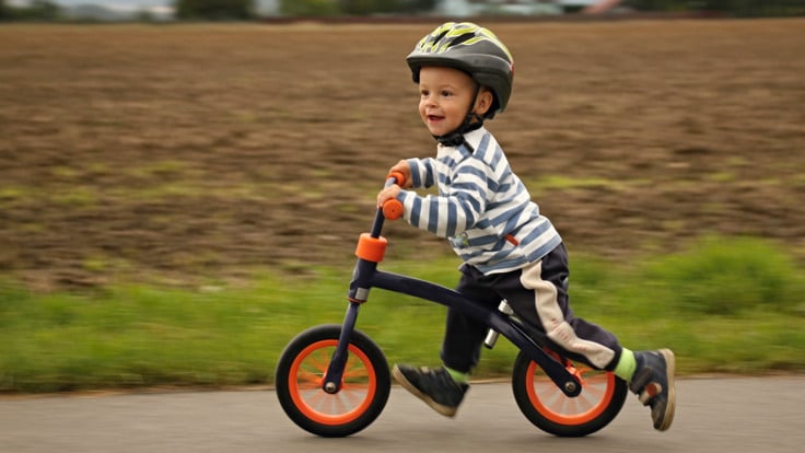 Pojke i f&ouml;rskole&aring;lder som cyklar med en balanscykel