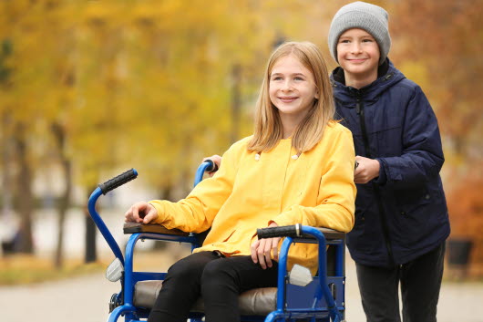 Två barn den ena kör den andra i rullstol